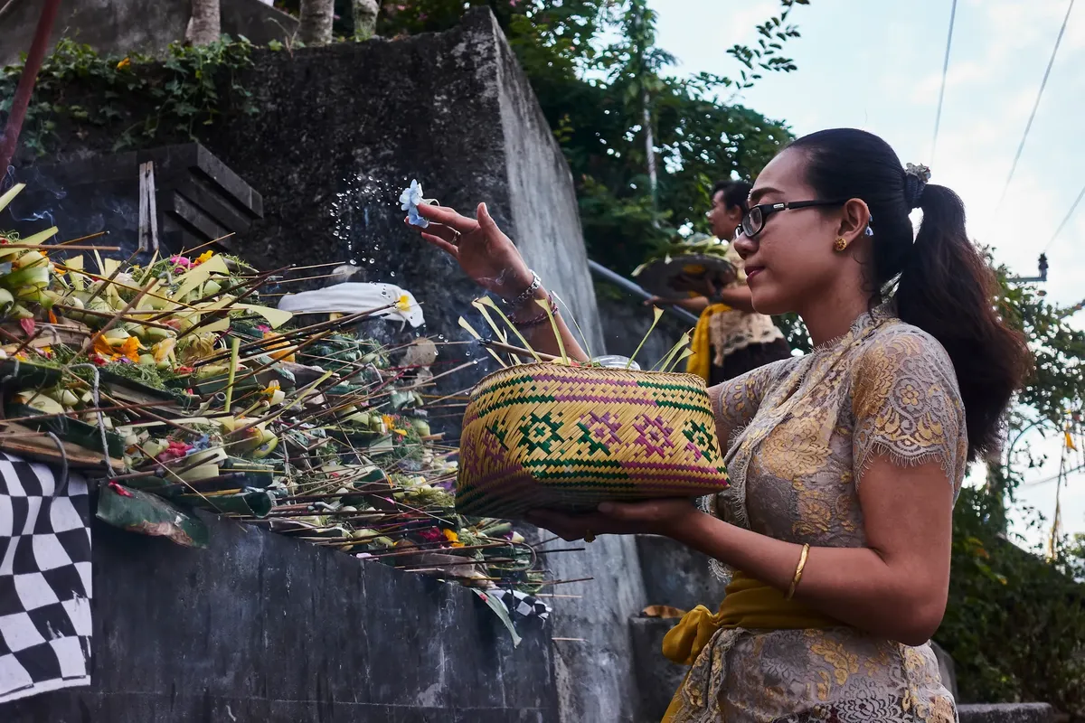 A woman performs a traditional Hindu offering ceremony in Bali, Indonesia.