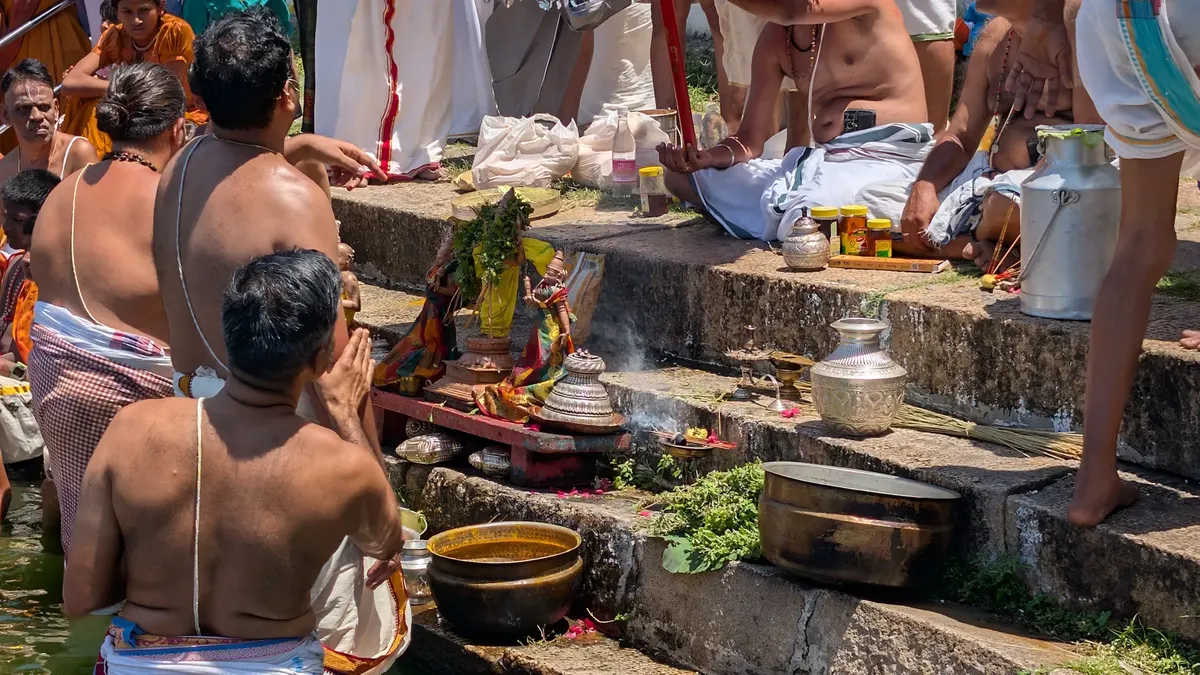 A vibrant Hindu ceremony taking place at a riverbank, featuring traditional attire and offerings.