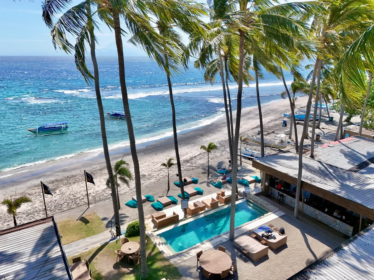 A stunning aerial view of a tropical beachfront resort with palm trees and ocean views in Bali.