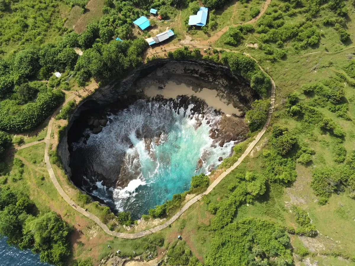 A breathtaking aerial view of Angel's Billabong in Nusa Penida, Bali showcasing vibrant turquoise waters in a rocky inlet.