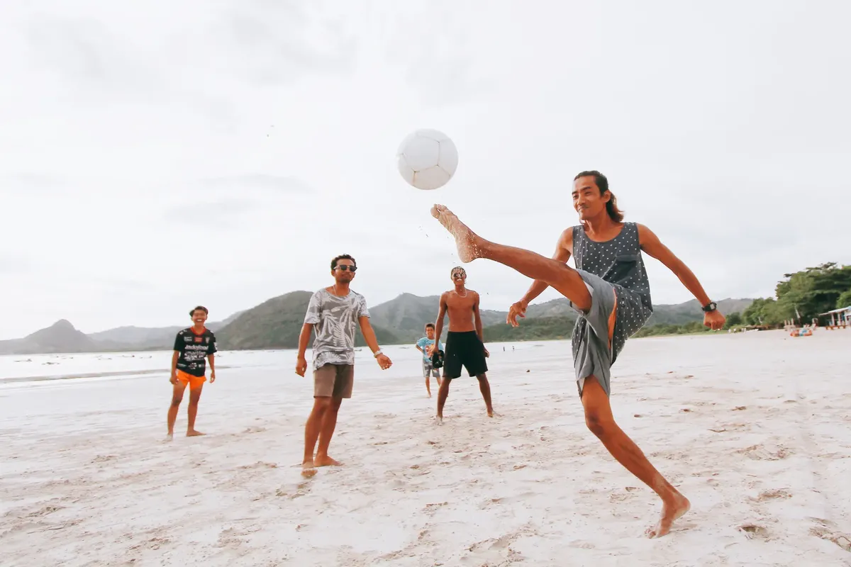 Group of young men enjoying a game of beach soccer in West Nusa Tenggara, Indonesia.