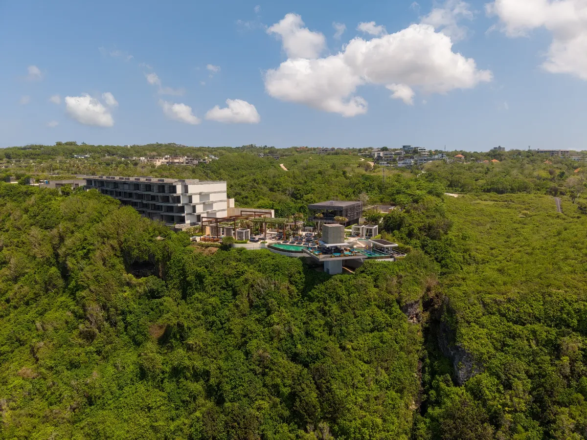 Aerial shot of a stunning cliffside resort in Bali, Indonesia, surrounded by lush greenery.